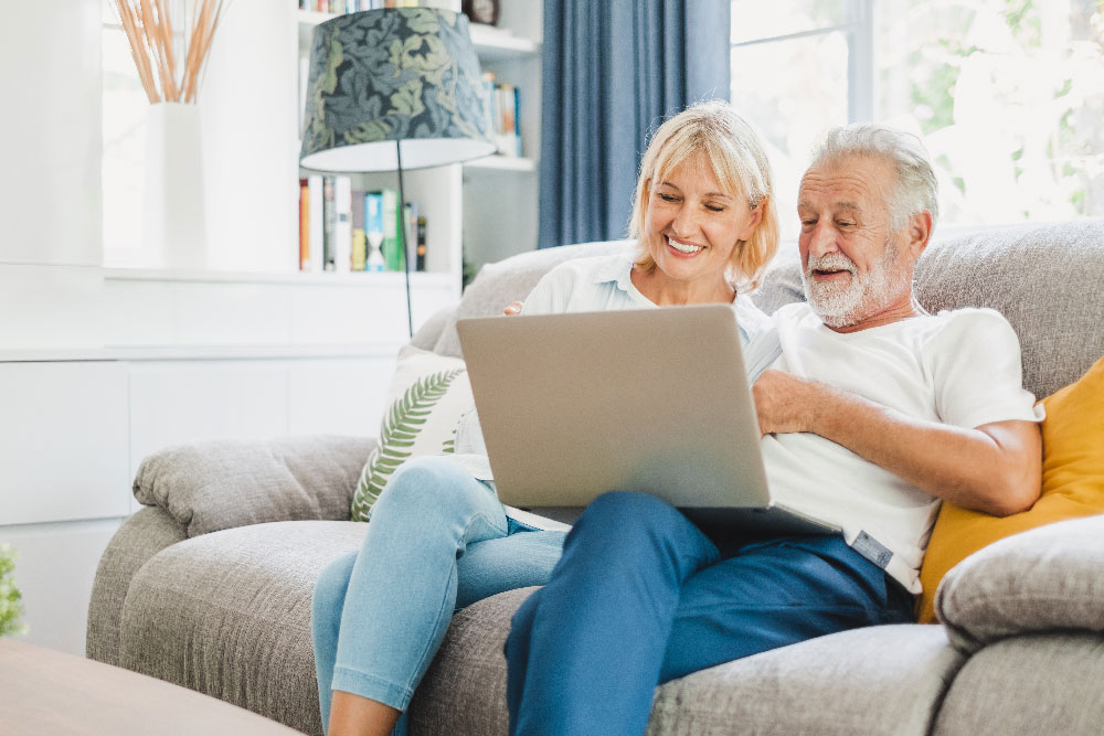 Senior-Couple-Sitting-on-Couch-with-Computer
