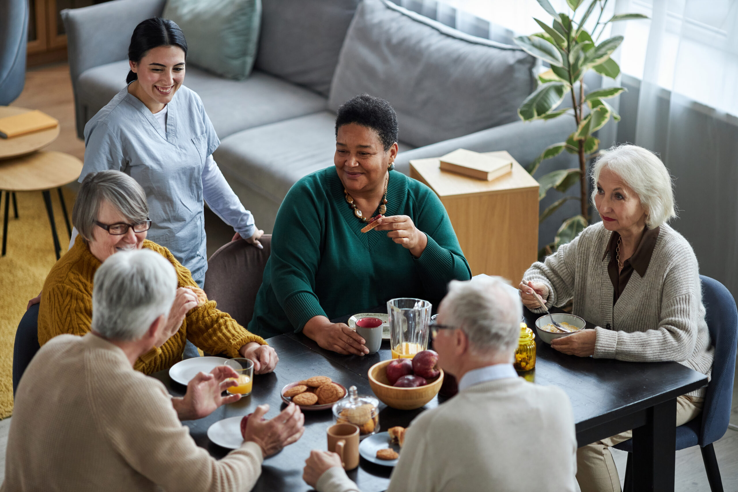 High angle view at group of senior people sitting at table together and smiling happily in retirement home