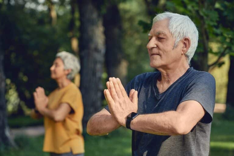 Older adults doing yoga outdoors.