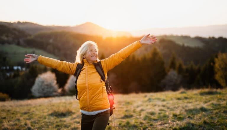 Older woman joyful on an open field.