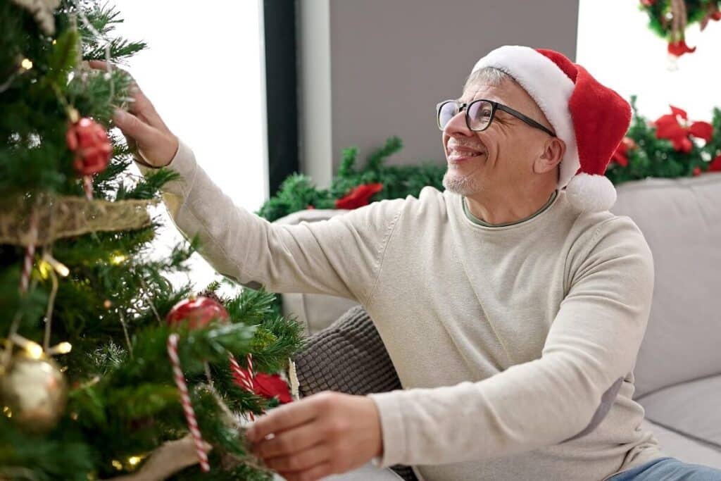 Older man decorating his Christmas tree